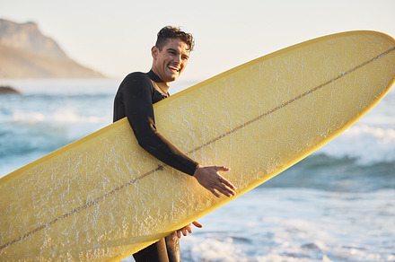 Portrait, man and surfing board, beach and summer training, freedom and happiness outdoors in South Africa. Portrait of happy surfer guy, ocean and sea water, relax and happiness for nature adventure, a Photo by Peopleimages.com