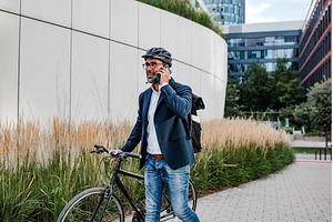 Cyclist making phone call, standing, a Business Photo by HalfPoint