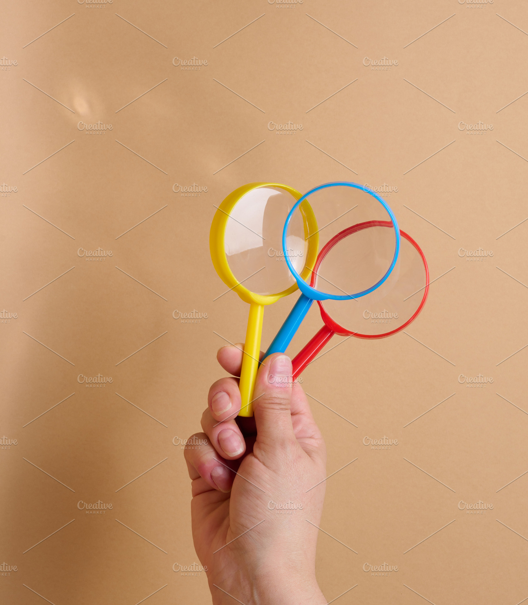 A person is holding three multicolored plastic magnifying glasse, a Business Photo by ndanko