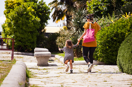 Rear view of a mother with her little daughter walking in the pa, a Person Photo by Bepslabor