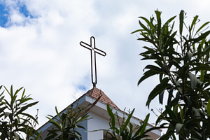 Iron cross standing on white church roof with cloudy sky, a Photo by Antonio Gravante Market