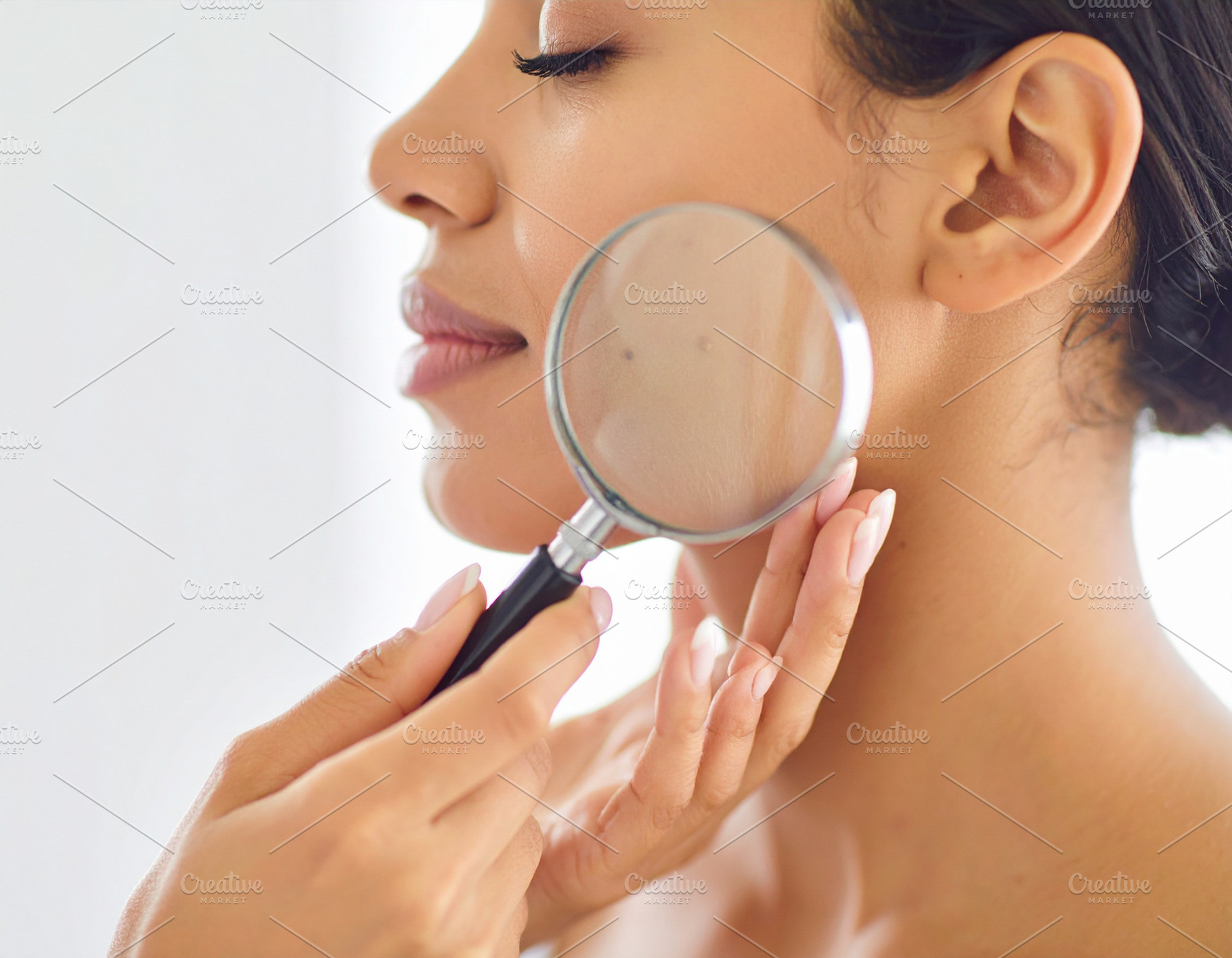 Female dermatologist examining a patient's cheek using a magnify, a Health & Medical Photo by DanFLCreativo