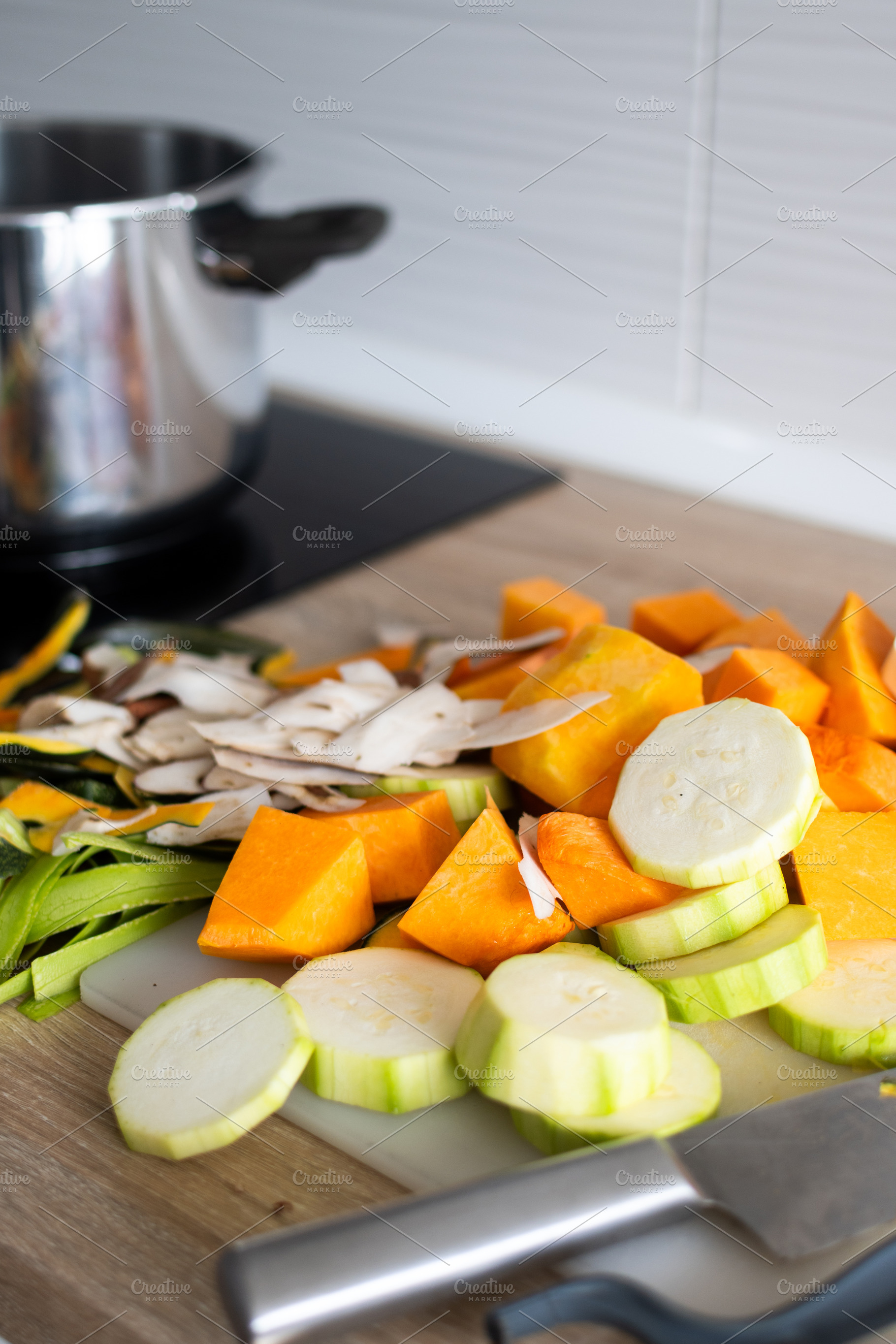 Fresh chopped vegetables on cutting board with pot on stove in kitchen, a Food & Drink Photo by etorres69