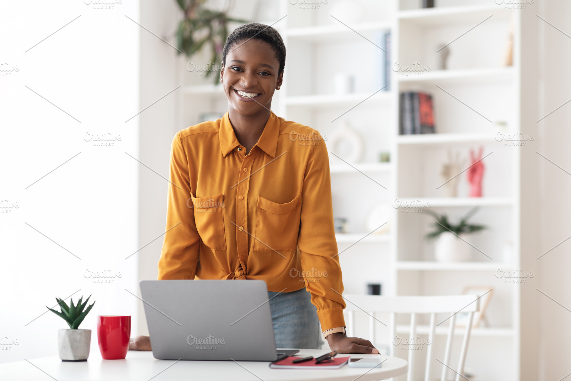 Positive short-haired african american woman posing at office, a Photo by Prostock-Studio