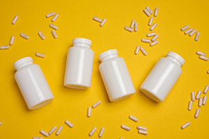 White capsules spilling from an open white plastic bottle, yello, a Health & Medical Photo by ndanko