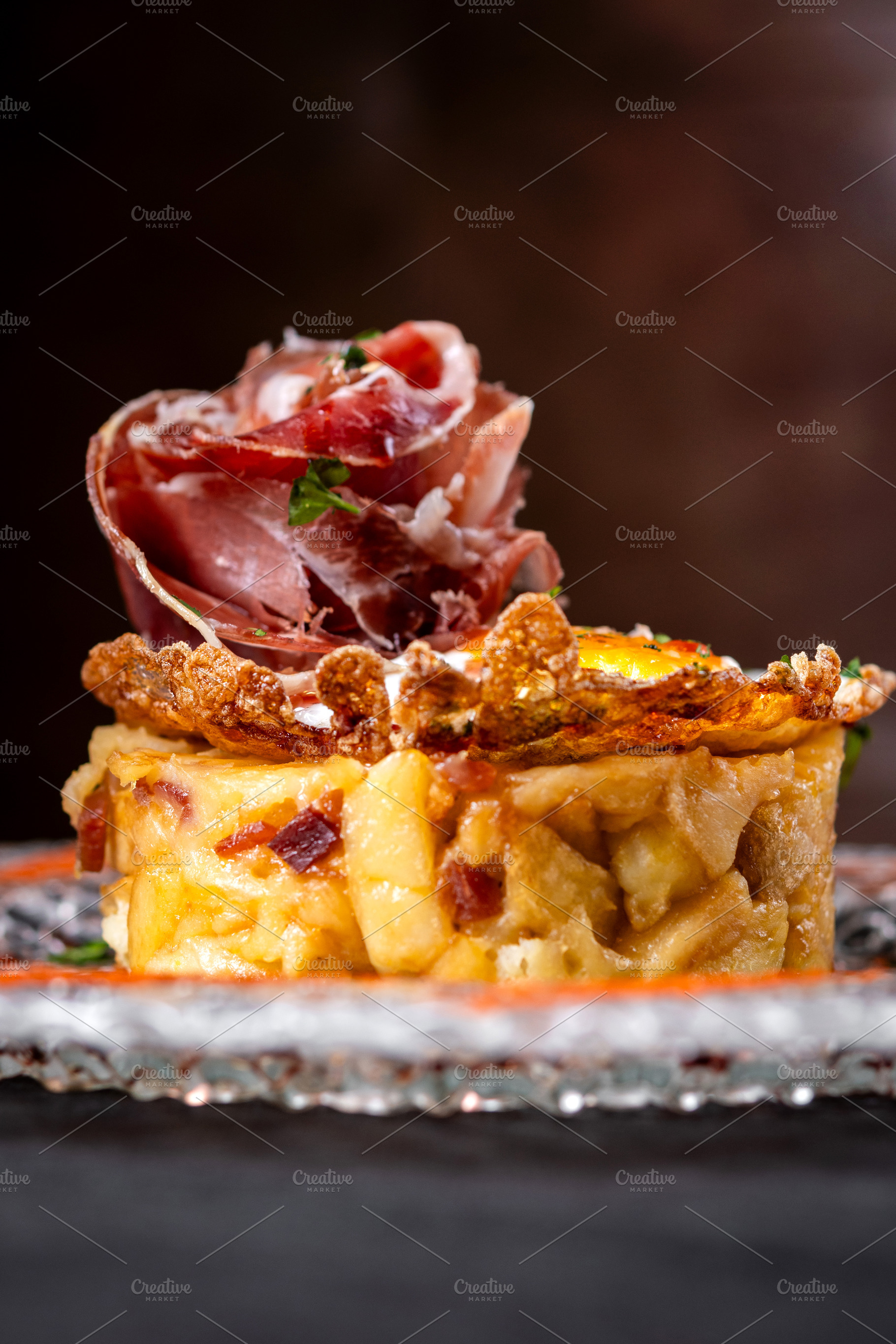 Traditional Spanish potato omelette with Iberian ham and crispy pork rind serve, a Food & Drink Photo by etorres69
