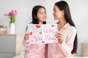 Satisfied happy korean young girl and millennial female read card and congratul, a Photo by Prostock-Studio
