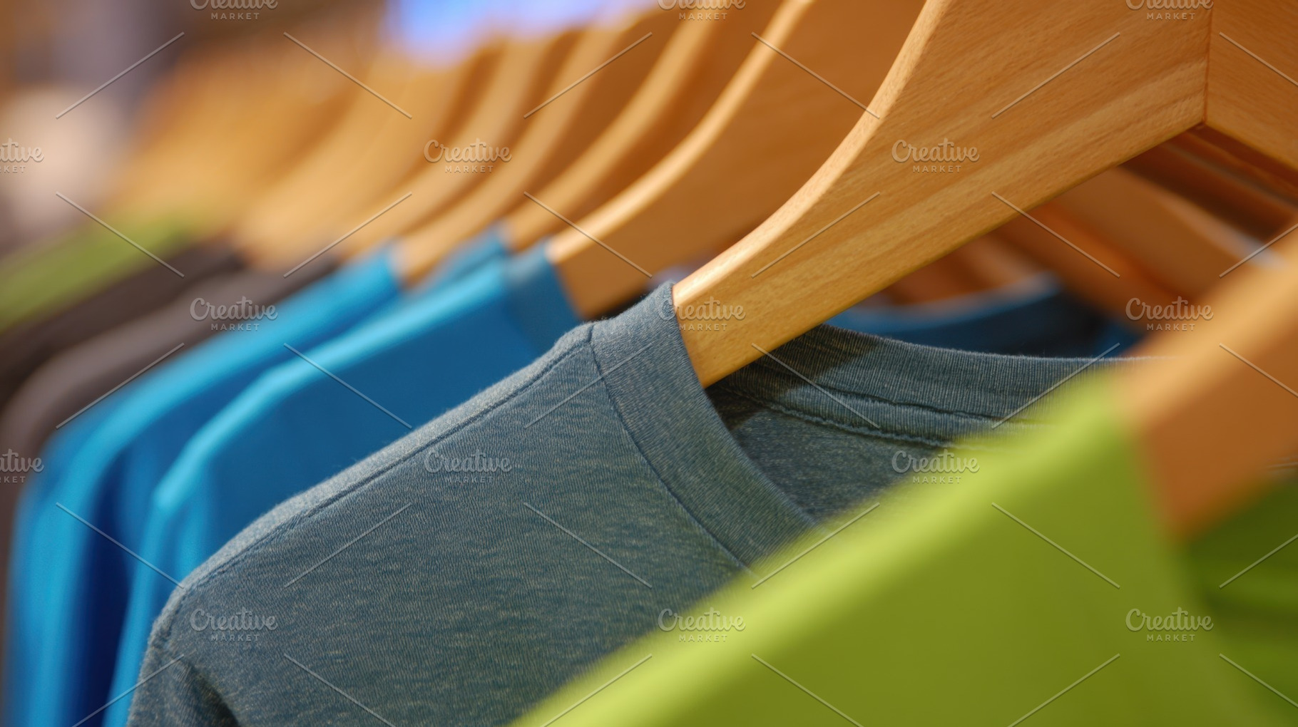 Colorful shirts hang on wooden racks, a Photo by Beautiful things