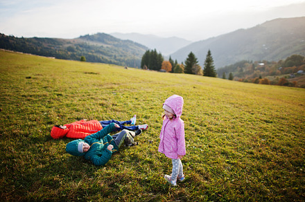 Three kids lying in the grass with a gorgeous mountain range in, a Person Photo by AS photostudio
