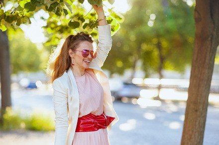 happy young woman in pink dress and white jacket in city, a Person Photo by Alliance Images
