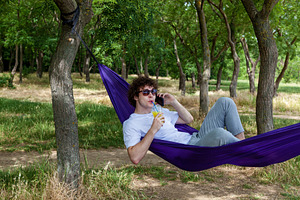 A young guy with curly hair is relaxing on a hammock on a hot summer day., a Person Photo by Photostock