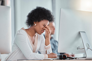 Tired, headache and woman on computer in office workspace with job depression, burnout and mental health risk. Business person working on desktop with workplace noise and stress, fatigue or migraine, a Photo by Peopleimages.com
