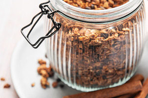 Granola cereal in glass jar with cinnamon sticks, a Food & Drink Photo by Olena Rudo