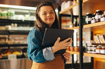 Supermarket employee with Down syndrome holding a digital tablet, a Person Photo by Jacob Lund