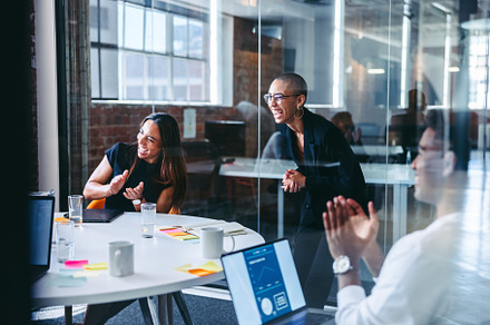 Cheerful businesspeople laughing while clapping their hands in a, a Person Photo by Jacob Lund