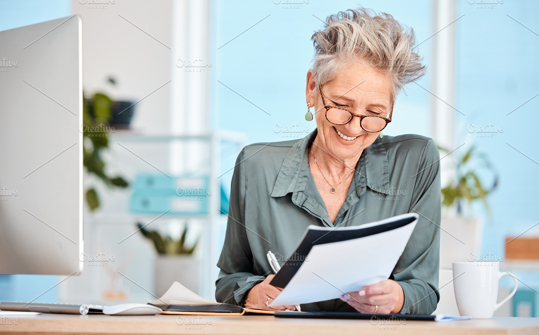 Finance paper, working and business woman writing notes in office, sitting at desk. Ideas, vision or senior woman with pen in hand to write, smile or paperwork, document and financial budget at desk, a Photo by Peopleimages.com