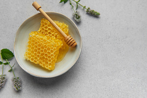 Honeycomb, honey dipper and fresh mint resting on a ceramic bowl, a Food & Drink Photo by Olena Rudo