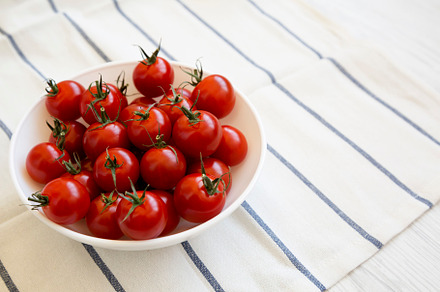Fresh Red Organic Cherry Tomatoes in a Bowl, side view. Copy spa, a Food & Drink Photo by LiudmylaChuhunova
