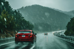 Red car driving in heavy rain on mou, a Photo by Pixeness Studio