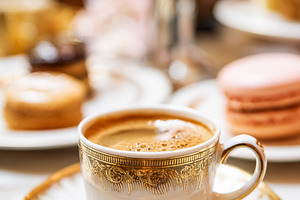 Hot coffee served in a refined gold rimmed porcelain cup on a ma, a Food & Drink Photo by Studio ANNA