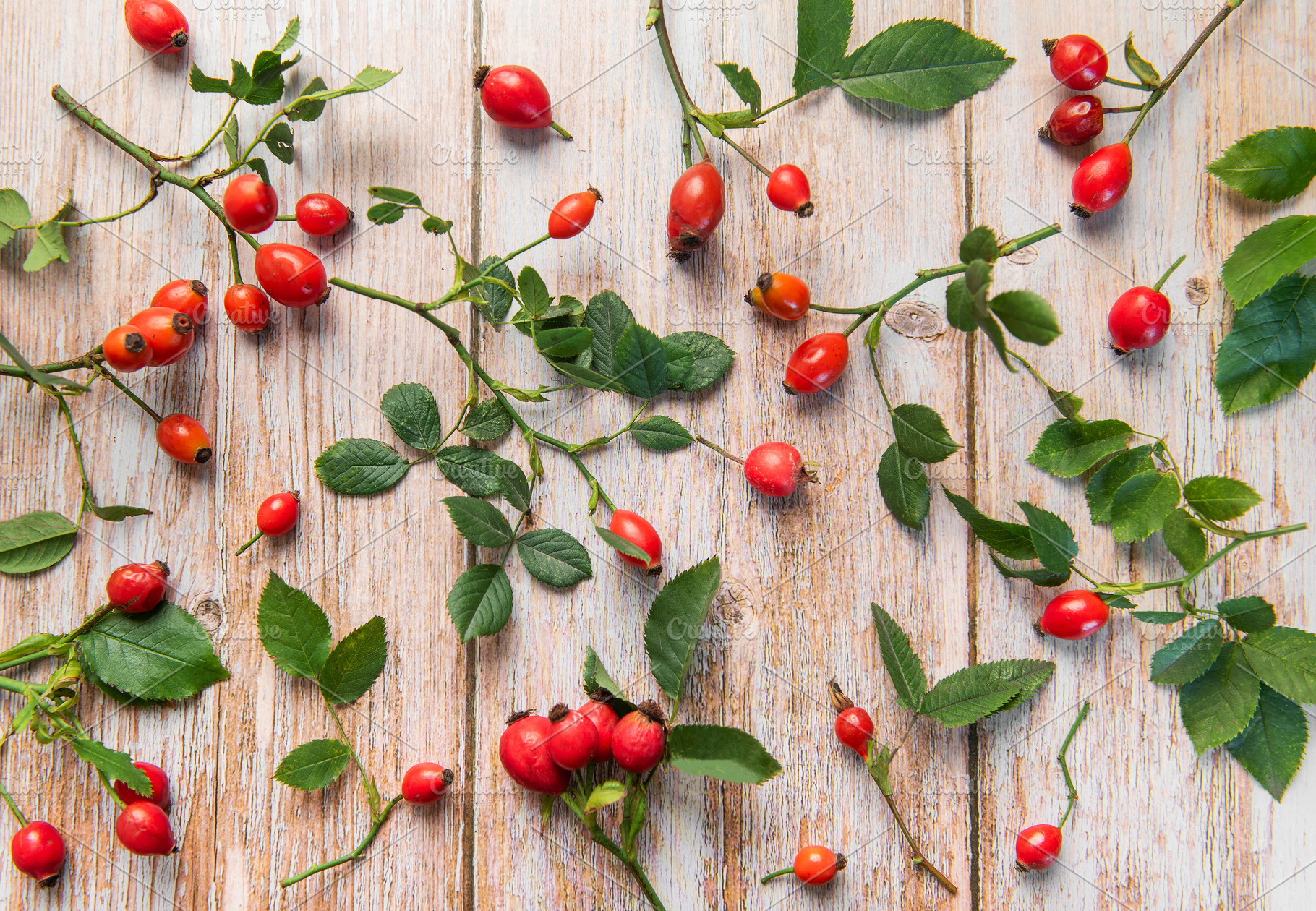 Rosehip berries and leaves arranged on rustic wooden table, a Food & Drink Photo by Olena Rudo
