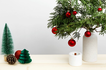 Vase with thuja branches, Christmas ornaments, pinecone, and candle for festive, a Photo by matucha