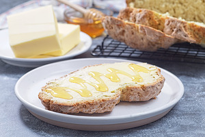 Freshly baked white Irish soda bread with butter and honey served on a plate, h, a Food & Drink Photo by iuliia_n