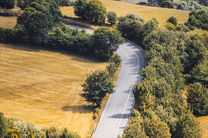 Curved rural road in valley, a Transportation Photo by SkyNext