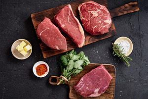 Raw rib-eye, roast beef, flank and rump steak on wooden cutting boards with her, a Food & Drink Photo by Asya Nurullina