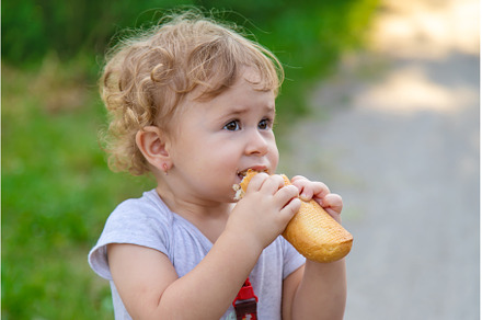 A child eats bread in the park, a Person Photo by yanadjana