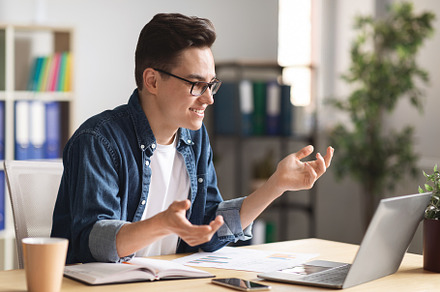 Young Male Entrepreneur Making Video Call With Laptop While Working In Office
