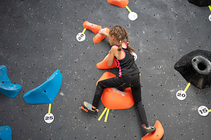 Determined girl climbing artificial rock wall at bouldering gym, a Photo by andreonegin market
