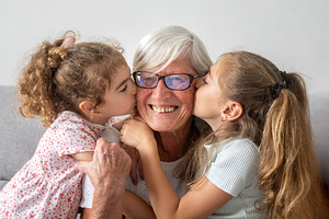 Granddaughters kissing their happy grandmother on the cheeks, a Person Photo by etorres69