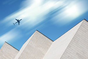 Airplane flying over modern building, a Transportation Photo by BOOCYS