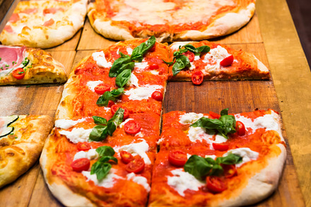 Many slices of pizza on wooden table, a Food & Drink Photo by Vapi
