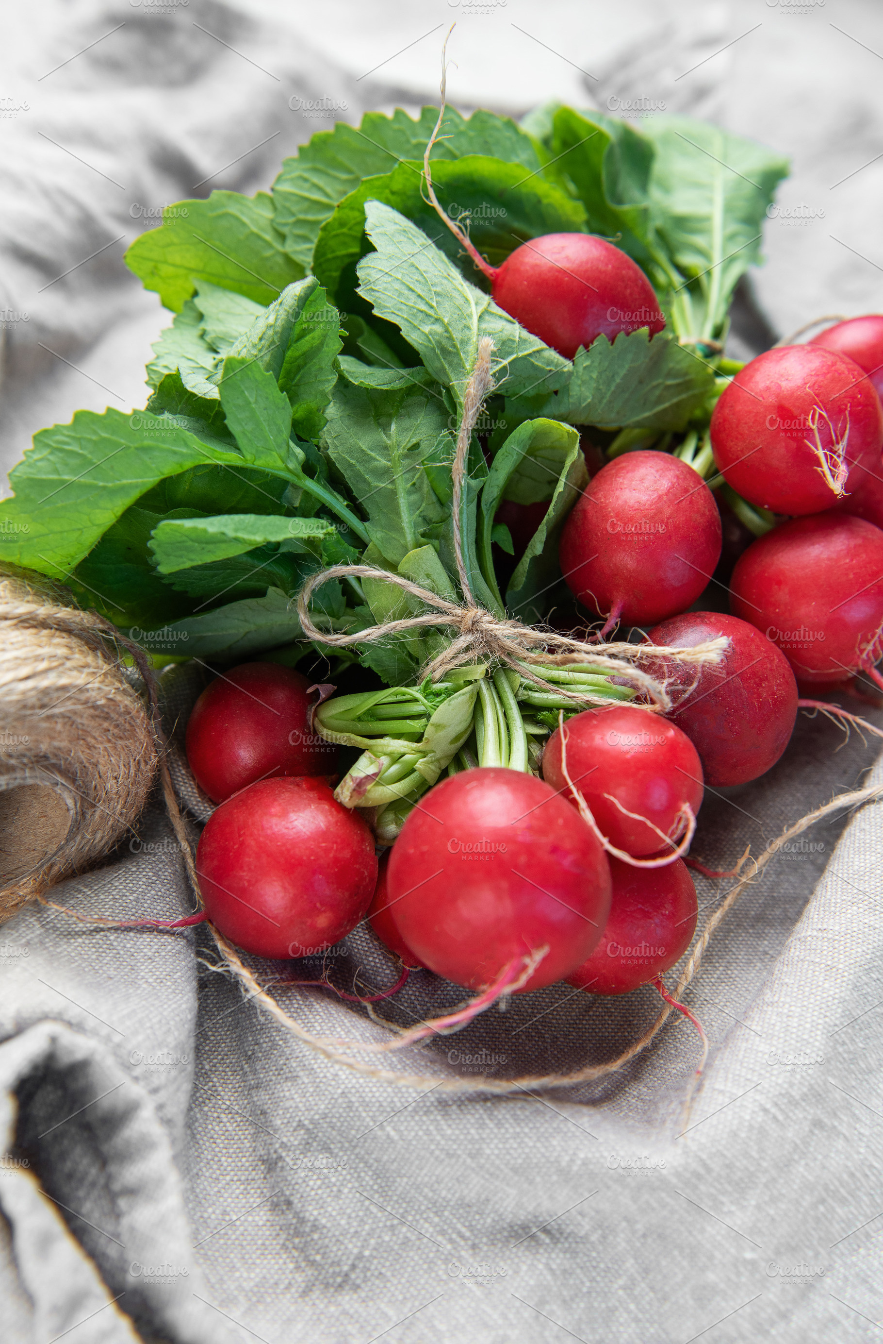 Fresh organic radishes with green leaves on rustic linen, a Food & Drink Photo by Olena Rudo