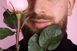 Close-up of a bearded man holding a pink rose in front of his fa, a Person Photo by Ales Munt
