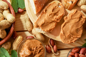 Homemade peanut butter and slices of bread on wooden outside, a Food & Drink Photo by Davizro's Market