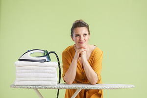 Woman resting by laundry pile with thoughtful look, a Person Photo by Alliance Images