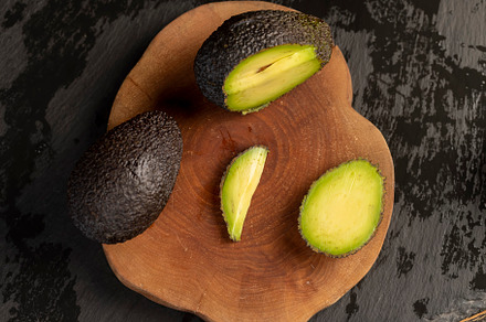 sliced small avocado with soft overripe flesh on a board, closeup