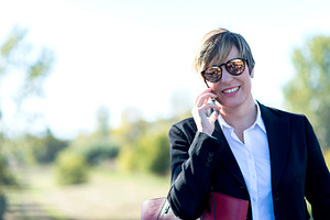 Smiling businesswoman talking on smartphone outdoors, a Photo by RF Images