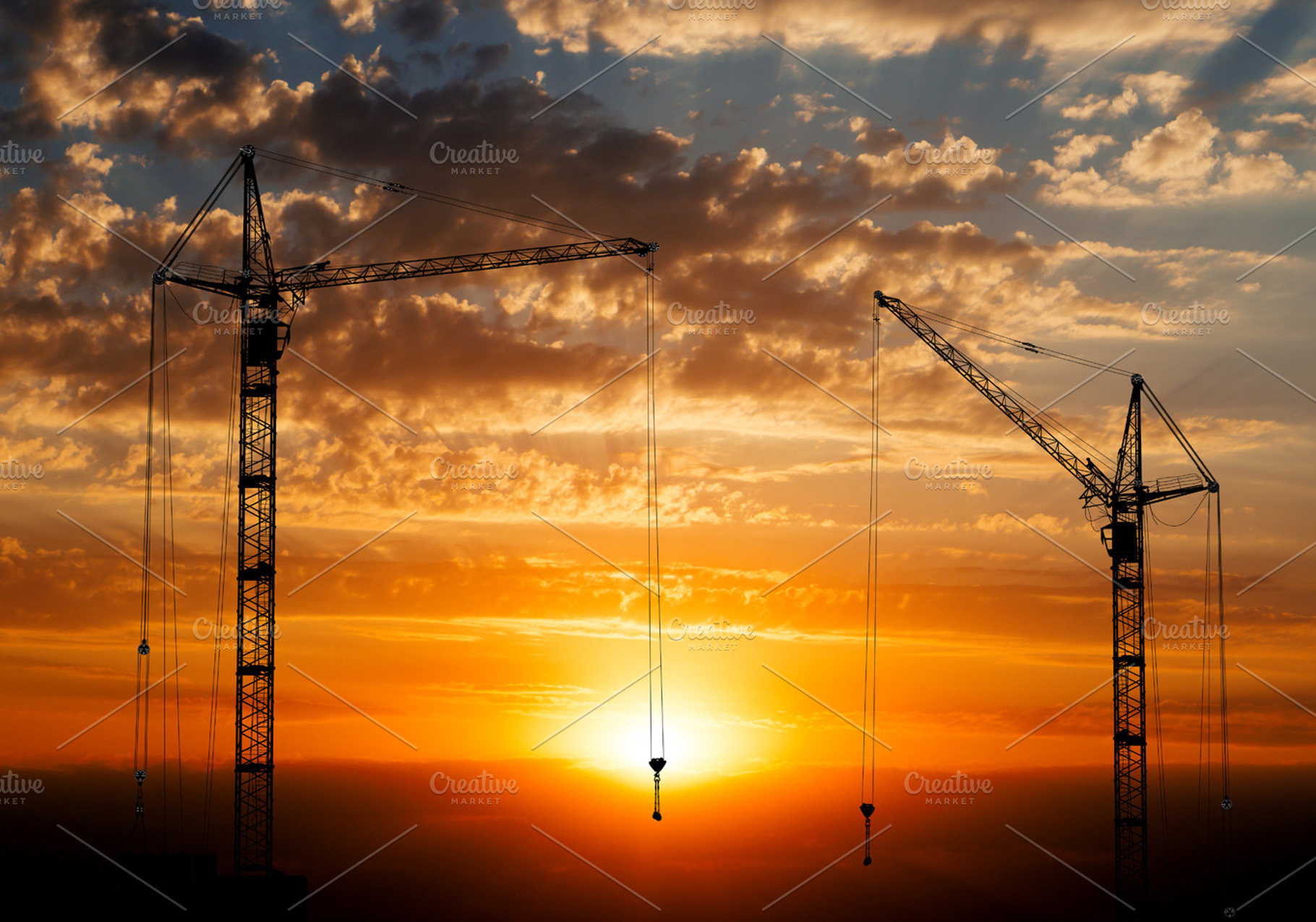 Hoisting cranes on sunset background, an Industrial Photo by PhotoVector