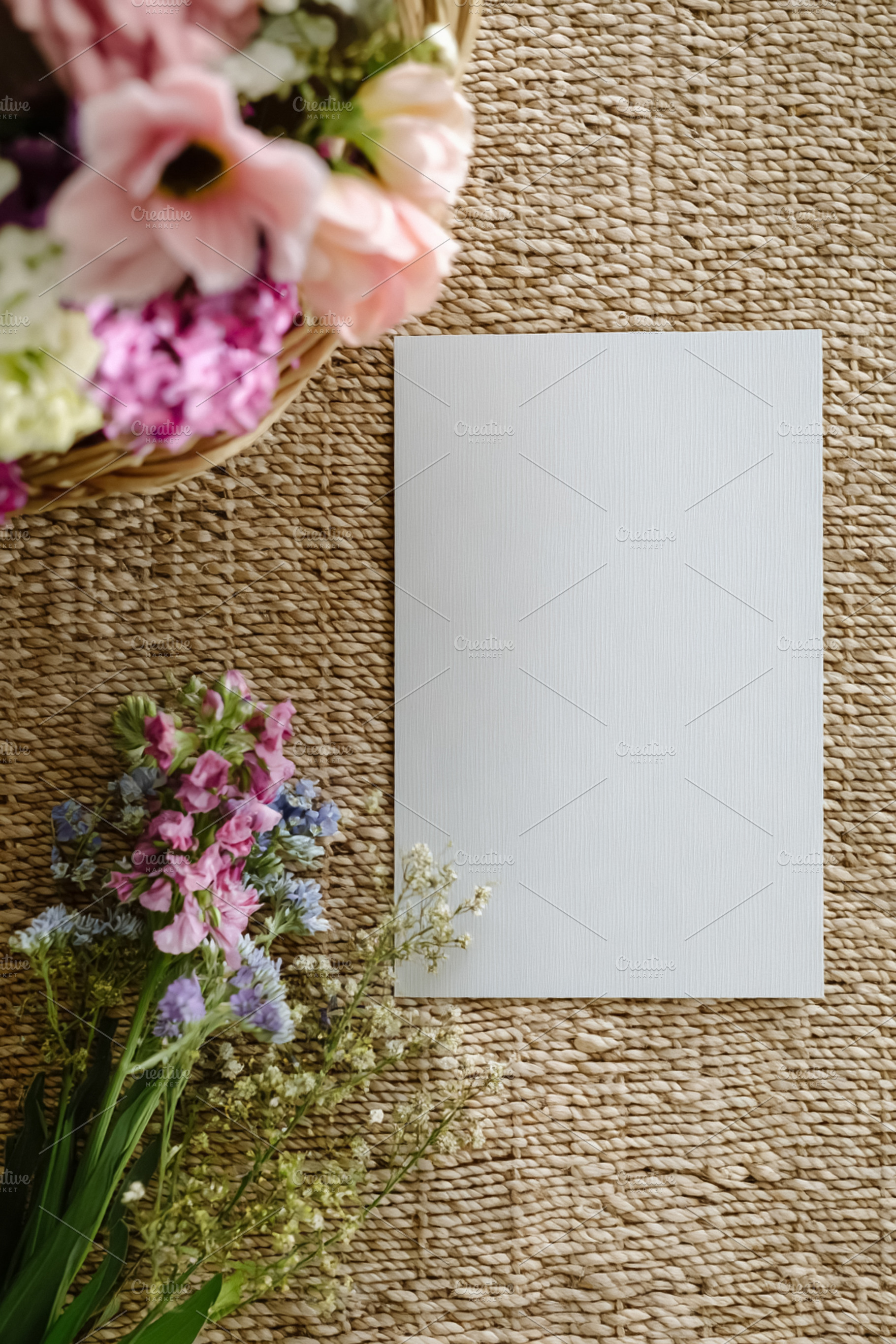 Blank white card mockup on rustic woven mat with assorted vibran, a Photo by Studio ANNA