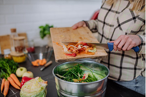 Woman throwing vegetable cuttings in, a Food & Drink Photo by HalfPoint