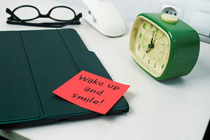 a bedside table with an alarm clock and a red note, a Photo by Nito
