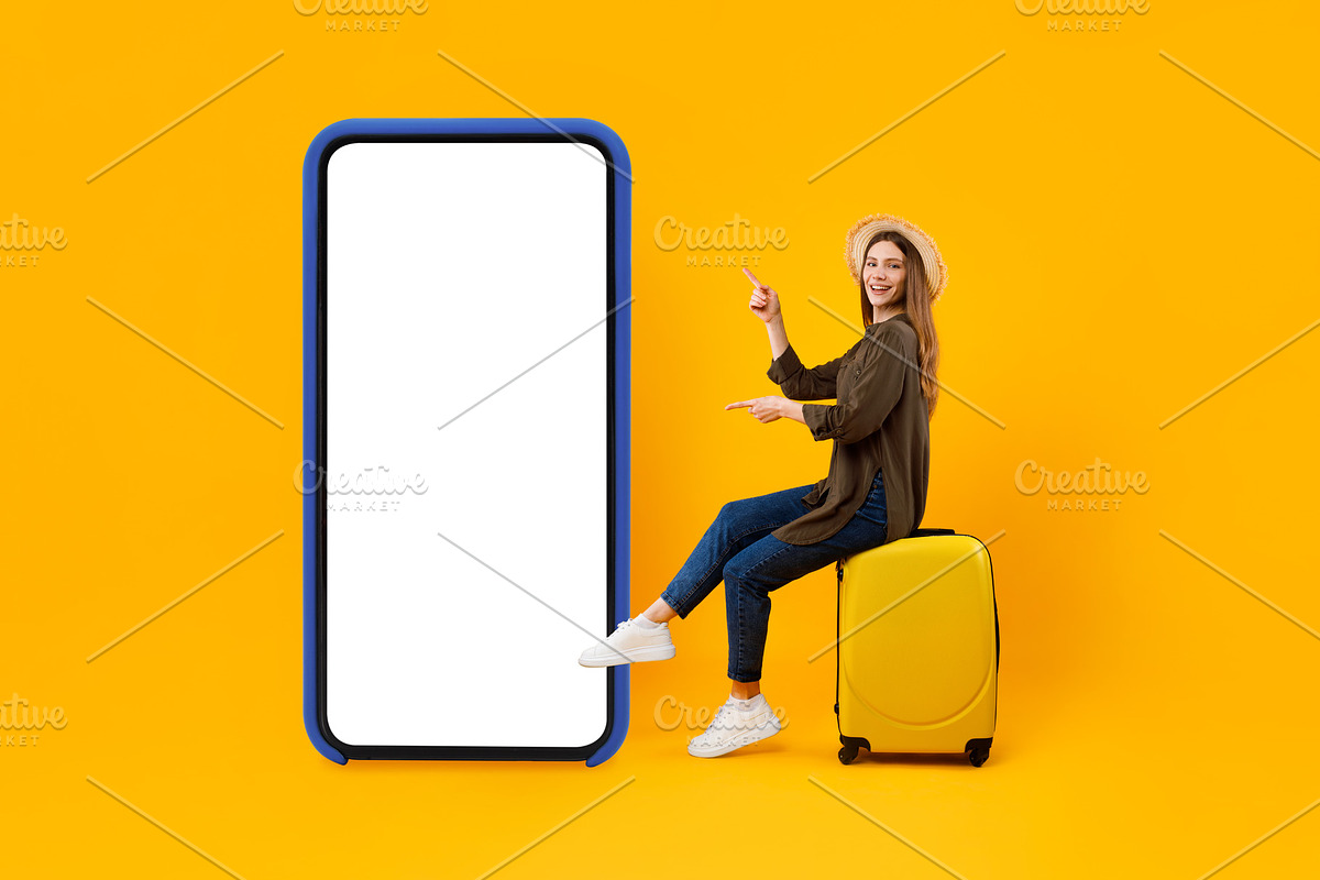 Tourist Lady Pointing At Big Smartphone Sitting On Suitcase, Studio, a Photo by Prostock-Studio (Photo 1 of 2)