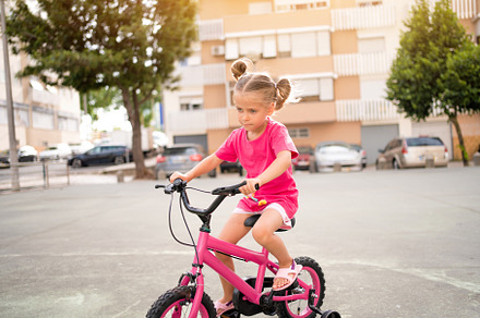 Cute little smiling girl riding bike bicycle in city on parking sunny summer da, a Person Photo by andreonegin market