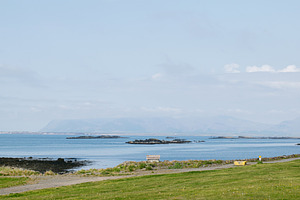 Scenic coastal view of grassy landscape with islands, distant mountains, and a, a Photo by AS photostudio