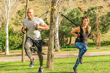 Fitness couple doing back legs exercise with trx fitness straps in park, a Sports & Recreation Photo by Iván Moreno STOCK PHOTO