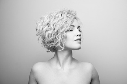 Headshot of gorgeous attractive young lady with curly hair smiling. Black and w